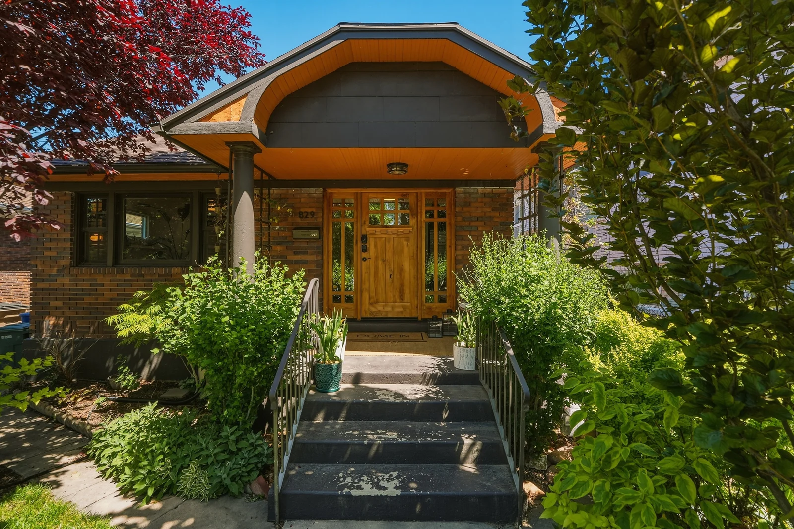Brick exterior featuring a distinctive covered entry with a natural wood door and sidelights
